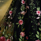 Close-up of a black embroidered skirt with pink and peach flowers and green leaves.