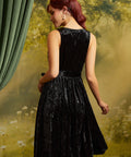 Rear three-quarter view of the sleeveless black velvet dress showing the back bodice, defined waist, and flared skirt.