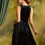 Rear three-quarter view of the sleeveless black velvet dress showing the back bodice, defined waist, and flared skirt.
