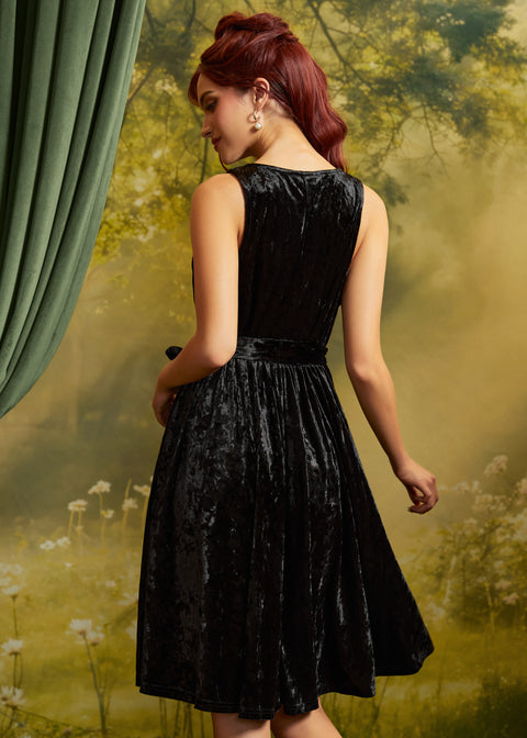 Rear three-quarter view of the sleeveless black velvet dress showing the back bodice, defined waist, and flared skirt.
