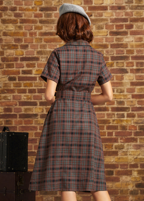 Model wearing a gray beret, photographed from behind in ModCloth's brown plaid Going Out and About Dress with short sleeves, a belted waist, and flared skirt.
