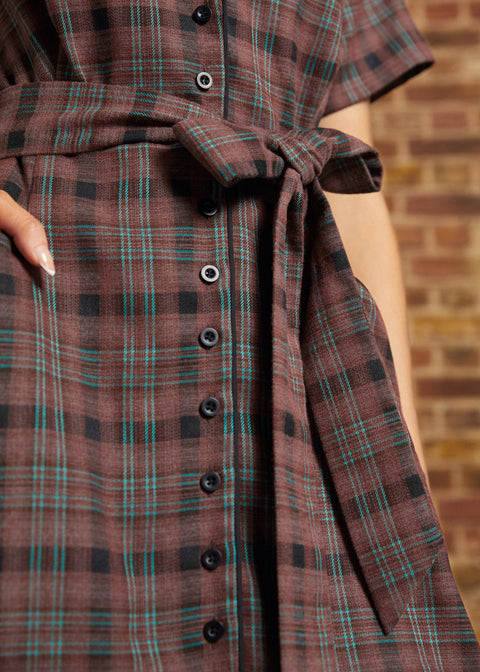 Close-up of the functional black button-front closure, matching plaid self-tie belt, and turquoise-accented brown checked fabric on a vintage inspired dress