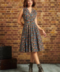 Full-length front view: Model standing in the ModCloth Mushroom Medley Carousel Cutie Dress with a sleeveless collared bodice, button-front closure, gathered flared skirt, and lace-up ankle boots.