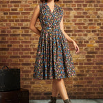 Full-length front view: Model standing in the ModCloth Mushroom Medley Carousel Cutie Dress with a sleeveless collared bodice, button-front closure, gathered flared skirt, and lace-up ankle boots.