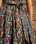 Back view of the Carousel Cutie Dress showing the mushroom print, sleeveless bodice, gathered skirt, elastic waist, and adjustable fabric ties knotted at the back waist.