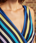 Close-up of the sleeveless faux-wrap V-neckline with diagonal multicolored stripes in shades of blue, yellow, turquoise, lavender, and peach.