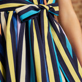 Close-up of the removable striped fabric sash tied into a bow at the front waist of the Instant Energy Faux-Wrap Dress.