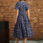Back view of navy cat and berry print midi dress showing short sleeves, elastic back waist, back zipper, and full gathered skirt.