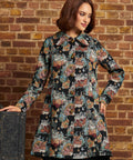 Front view of women's vintage-inspired tapestry coat featuring long sleeves, ornate gold-tone buttons, pointed collar and flared silhouette.