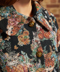 Detail view of oversized pointed collar, decorative gold-tone buttons and intricate cat and floral tapestry design.