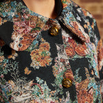 Detail view of oversized pointed collar, decorative gold-tone buttons and intricate cat and floral tapestry design.