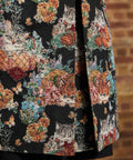 Close-up of tapestry coat hem showing orange and gray kittens among colorful flowers, and back pleat opening.