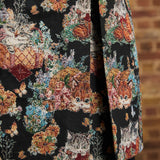 Close-up of tapestry coat hem showing orange and gray kittens among colorful flowers, and back pleat opening.