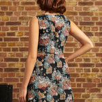 Rear view of the Tallulah mini dress showing its fitted sleeveless bodice, center back zipper, and multicolored cat-and-floral tapestry pattern.