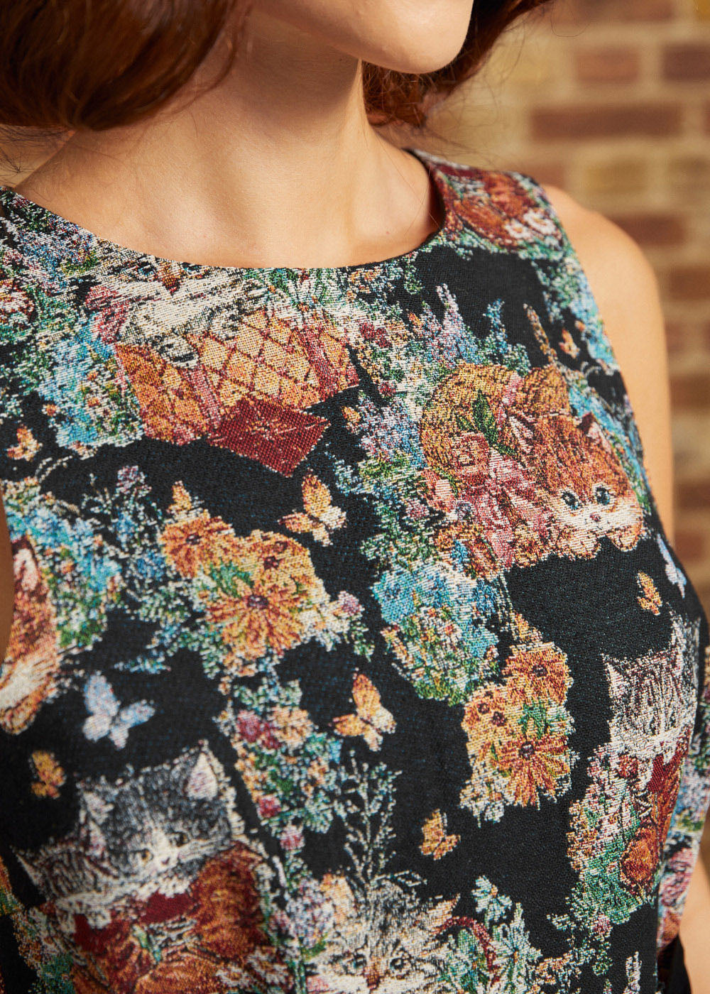 Close-up of the sleeveless round neckline and woven-look tapestry design featuring kittens, butterflies, flowers, and multicolored foliage on a ModCloth dress