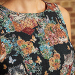 Close-up of the sleeveless round neckline and woven-look tapestry design featuring kittens, butterflies, flowers, and multicolored foliage on a ModCloth dress