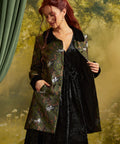 Three-quarter view of the Eloise Empire Waist Coat worn open over a black velvet dress, showing the long sleeves, contrasting black cuffs, and cat print.