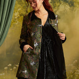 Three-quarter view of the Eloise Empire Waist Coat worn open over a black velvet dress, showing the long sleeves, contrasting black cuffs, and cat print.