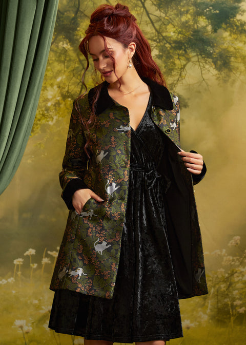 Three-quarter view of the Eloise Empire Waist Coat worn open over a black velvet dress, showing the long sleeves, contrasting black cuffs, and cat print.