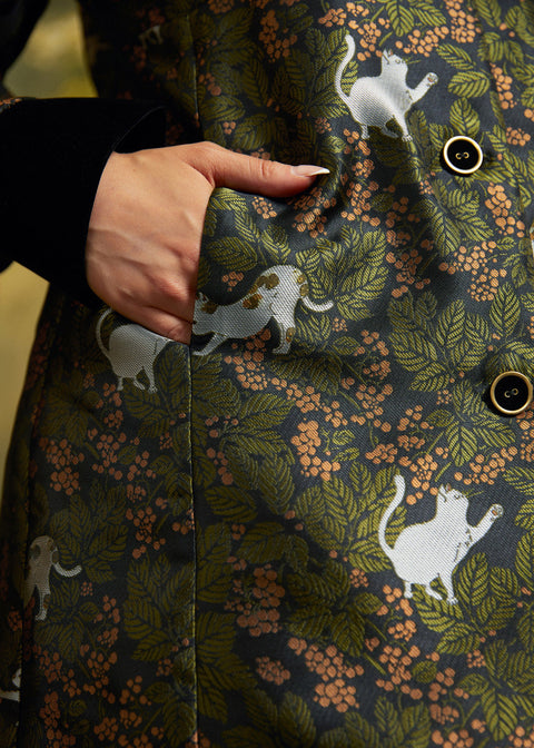 Close-up of the functional side pocket on the Eloise Empire Waist Coat, showing the white cat motif, green foliage, and button-front detailing.