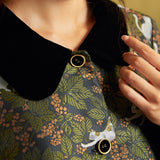 Close-up of the coat's contrasting black Peter Pan collar and gold-rimmed black buttons against the green botanical cat print.
