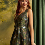 A woman wearing a sleeveless V-neck midi dress with a dark green crisscross jacquard pattern featuring white cats and orange floral details, posed next to a dark green curtain.