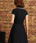 Back view of the Lottie black fit-and-flare dress showing its lace-trimmed collar, short sleeves, fitted waist, and flared skirt.