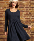 Model wearing a navy cable-textured long sleeve fit-and-flare mini dress with a scoop neckline and empire waist, styled with a white beret.