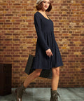 Three-quarter side view of model wearing navy cable-knit fit-and-flare dress with ankle boots and white beret.