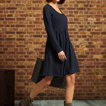 Three-quarter side view of model wearing navy cable-knit fit-and-flare dress with ankle boots and white beret.
