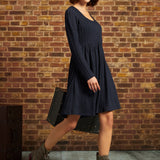 Three-quarter side view of model wearing navy cable-knit fit-and-flare dress with ankle boots and white beret.