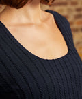 Close-up of scoop neckline and raised vertical cable-knit texture on navy dress.