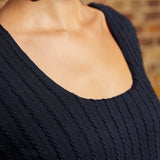 Close-up of scoop neckline and raised vertical cable-knit texture on navy dress.