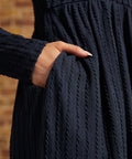 Close-up of hand in side pocket showing the navy textured cable-knit fabric and long sleeves on a ModCloth dress.