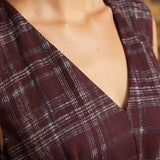 Close-up of the V-neckline on a burgundy plaid dress, highlighting the intersecting gray-blue lines and tailored bodice.