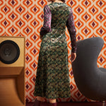 Woman wearing green and burgundy mixed paisley midi dress with burgundy boots, full back view