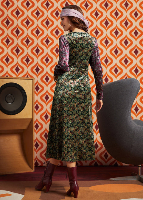 Woman wearing green and burgundy mixed paisley midi dress with burgundy boots, full back view