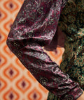 Close-up of burgundy paisley long sleeve and cuff beside contrasting green paisley bodice