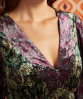 Close-up of deep V-neckline on green and burgundy paisley dress showing contrasting coordinating prints