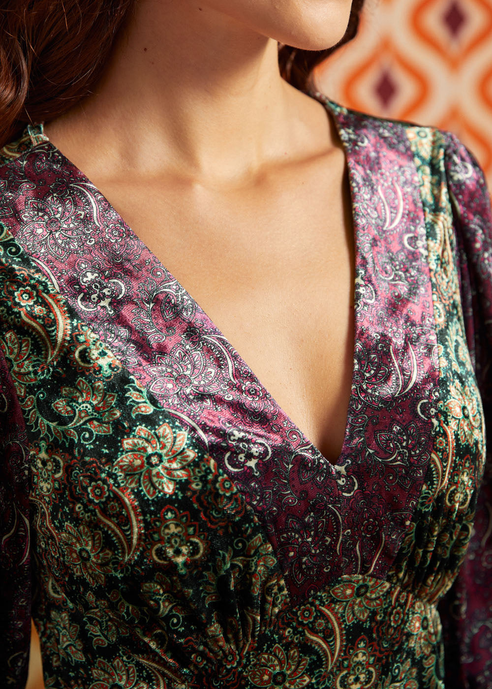 Close-up of deep V-neckline on green and burgundy paisley dress showing contrasting coordinating prints