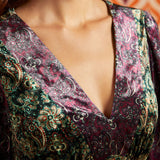 Close-up of deep V-neckline on green and burgundy paisley dress showing contrasting coordinating prints