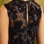 Detailed view of the fitted waist and gathered skirt on a ModCloth party dress highlighting the textured black floral embroidery and scattered sequins.