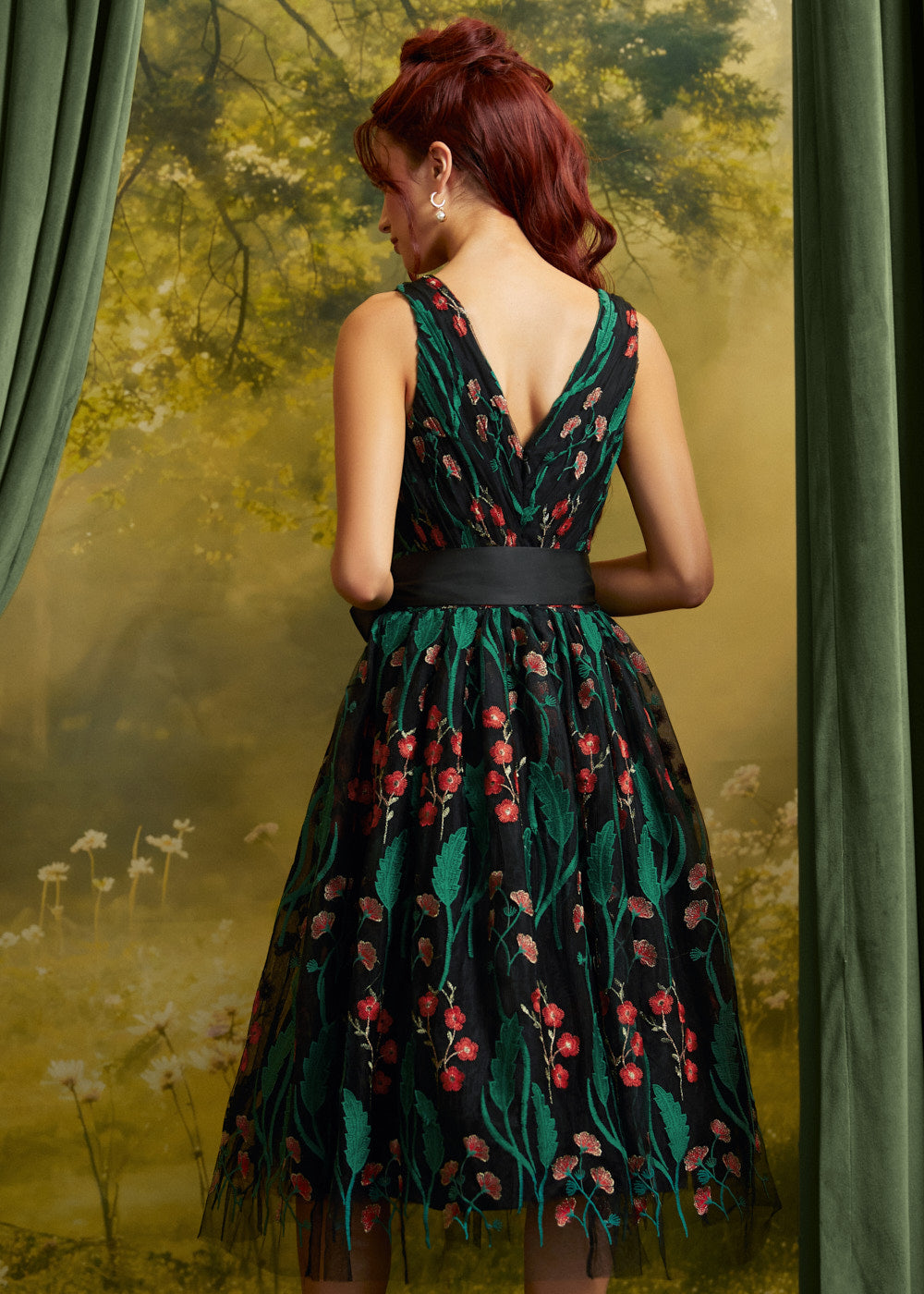 Back view of the floral embroidered midi dress showing the V-back neckline, fitted waist, black sash, and flowing skirt.