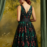 Back view of the floral embroidered midi dress showing the V-back neckline, fitted waist, black sash, and flowing skirt.