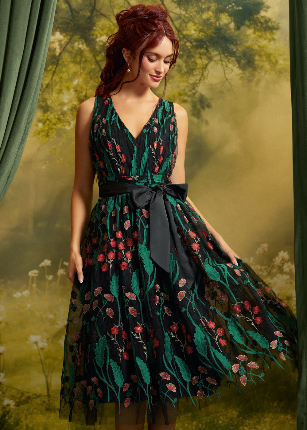 Front view of the Memory Lane Fit & Flare Dress featuring coral floral embroidery and green botanical vines on black mesh, a V-neckline, and a black ribbon waist bow.