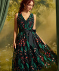 Front view of the Memory Lane Fit & Flare Dress featuring coral floral embroidery and green botanical vines on black mesh, a V-neckline, and a black ribbon waist bow.