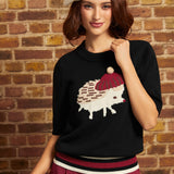Model wearing the black ModCloth Hattie Half-Sleeve Sweater featuring a cream hedgehog in a burgundy beret with a pom-pom, striped ribbed hem, and elbow-length sleeves, styled with burgundy trousers and a cream beret.