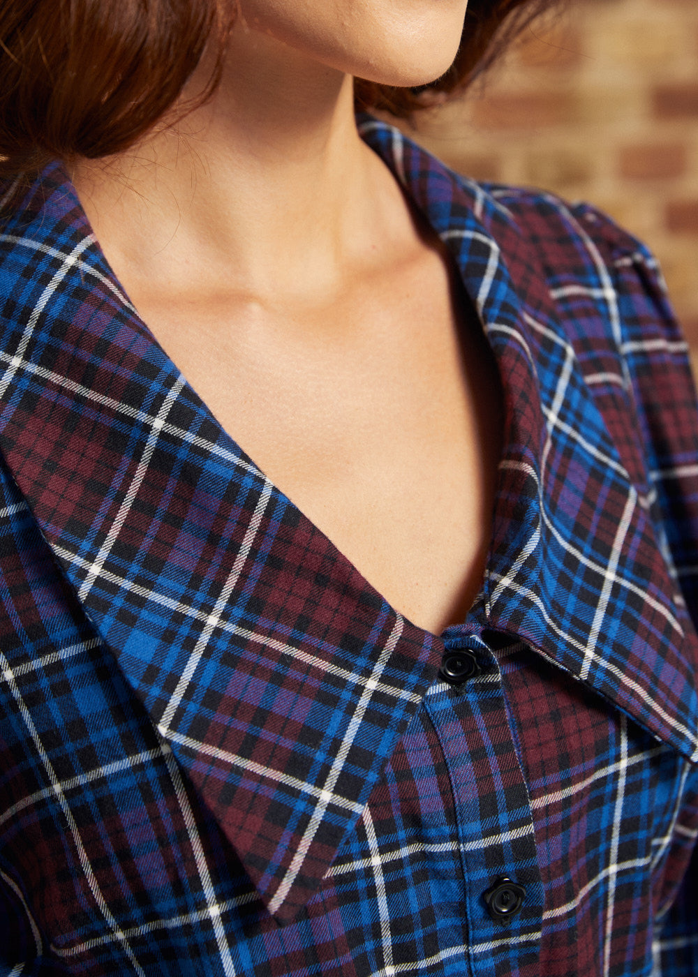 Close-up of the Petal Picnic plaid blouse showing its oversized pointed collar, V-shaped neckline, and functional black buttons in burgundy, blue, and white plaid.