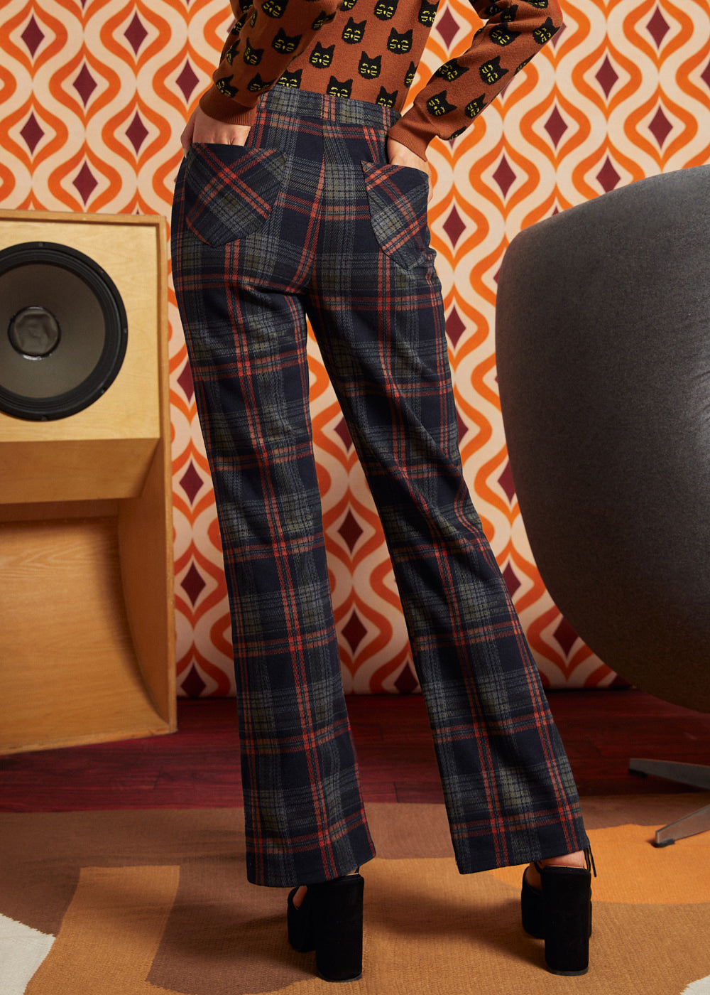 Woman wearing dark navy plaid flare pants with brown cat cardigan and black platform heels, back view showing two patch pockets