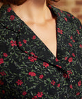 Close-up of the notched collar and black button-front bodice on a vintage-inspired corduroy dress with red floral print.